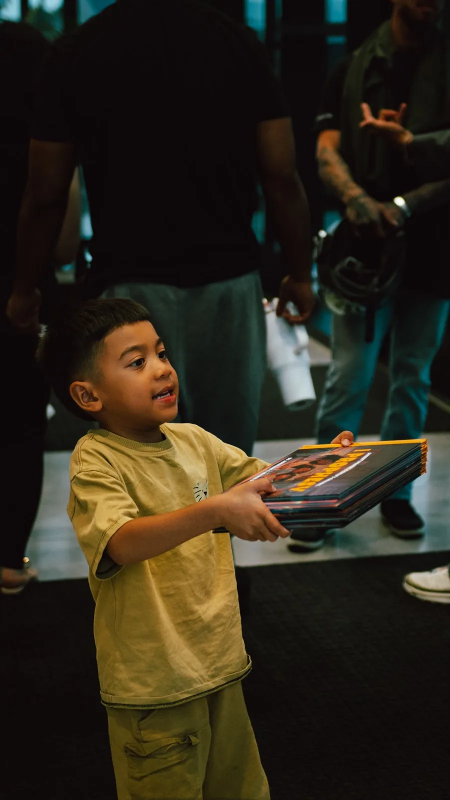 A young boy carrying a stack of Latter House children's books out of a church seminar