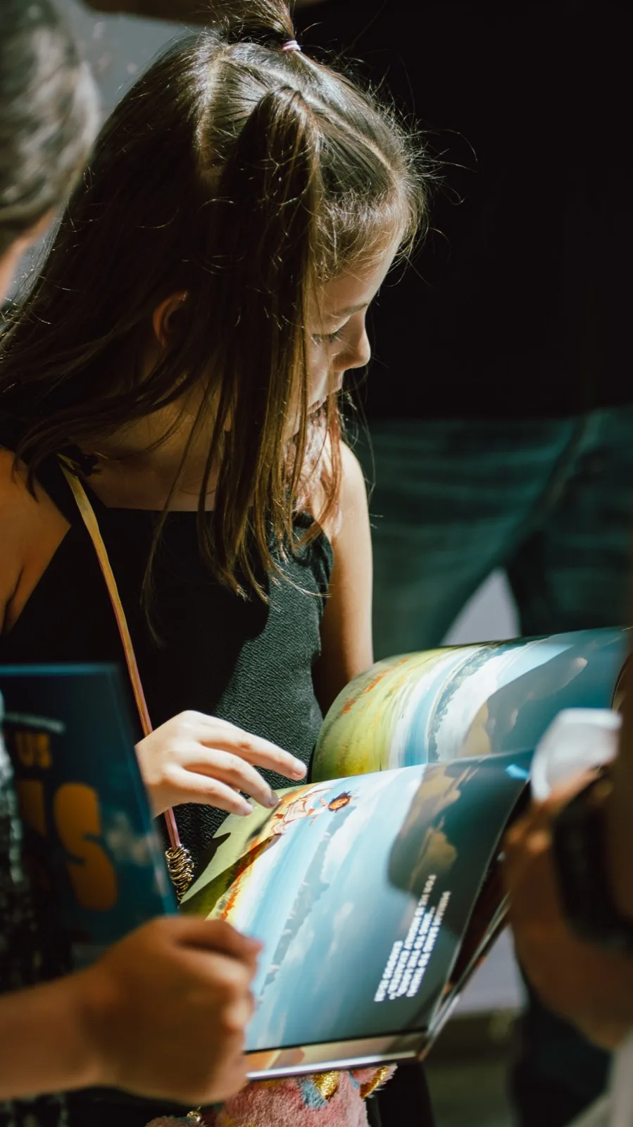 A girl reading an open Latter House picture book at a church seminar